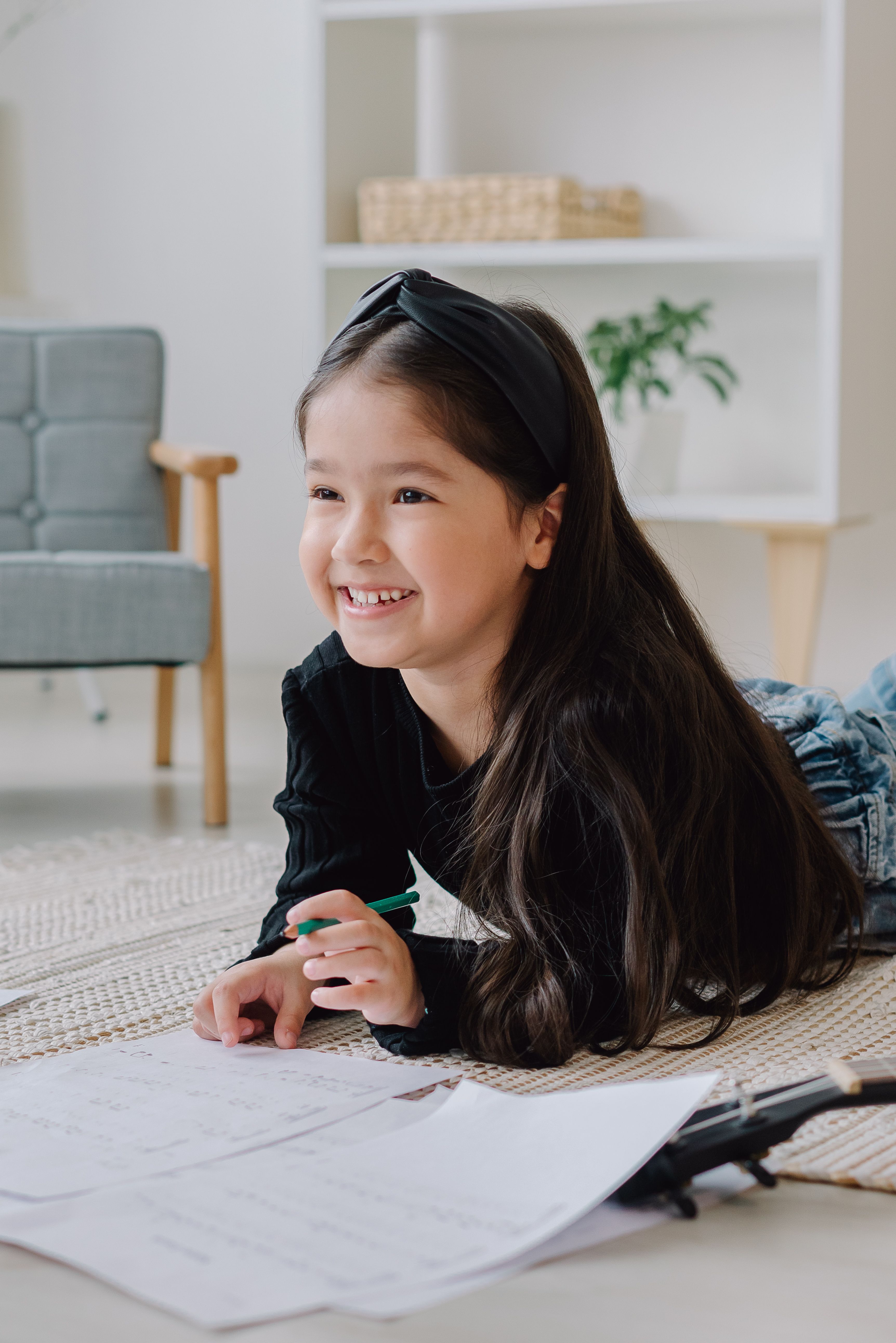 A smiling girl writing on the floor at home